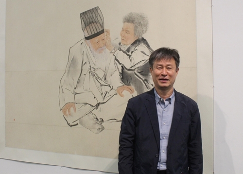 수묵화의 대가 김호석 화백이 전시 중인 자신의 그림 앞에서 포즈를 위하고 있다.