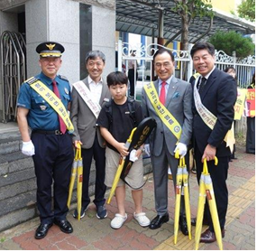  기관장들이 교통안전 문구가 담긴 우산을 배부  하고있다