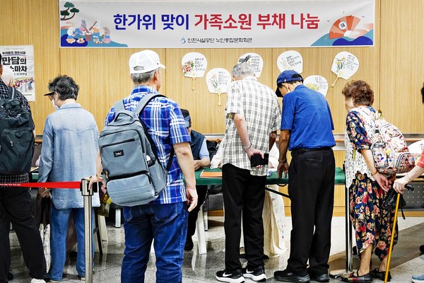 '가족소원 부채 나눔' 코너,에서 가족소원을 서예 봉사자들이 현장에서 부채에 써넣어 나눠주고 있다. 