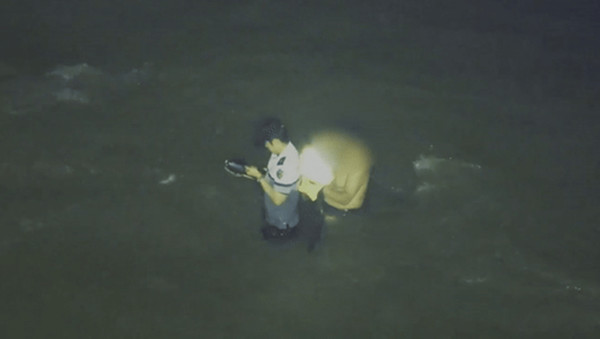 갯벌에 고립된 중국인 노인 구조를 위해 자신의 구명조끼를 벗어주고 있는 이재석 경사의 모습이 찍힌 영상 캡처 (사진=인천해양경찰서 제공)